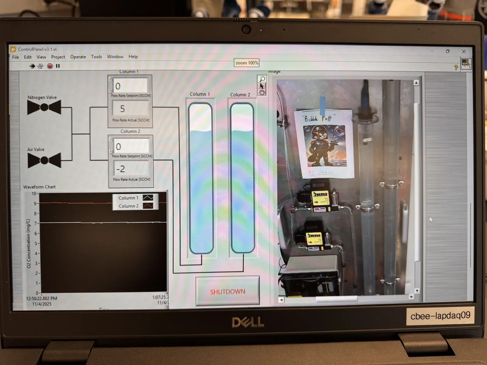 A laptop showing the LabVIEW control panel: valve and column controls on the left, the camera's live view of the rig on the right