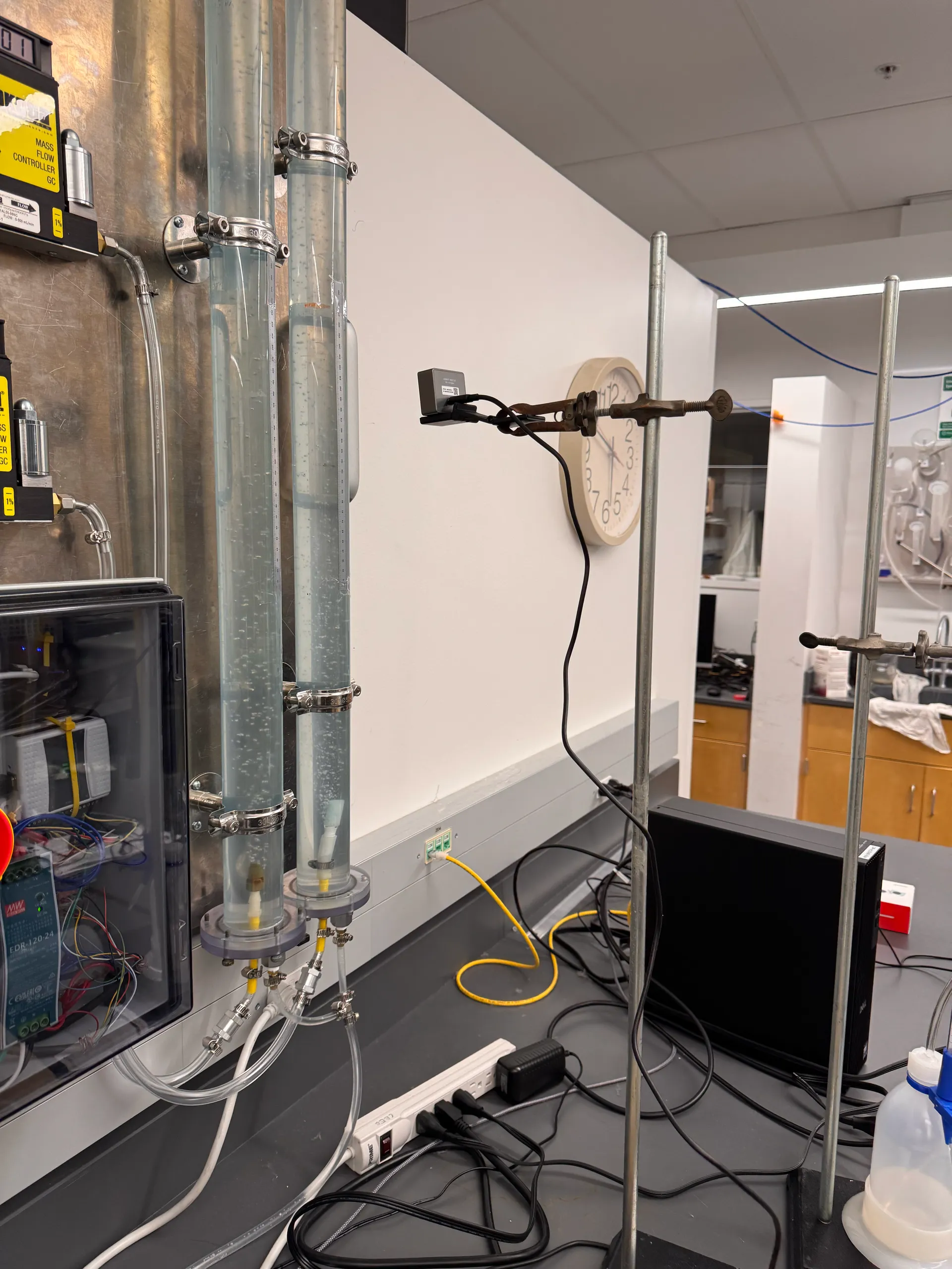 A candidate camera held by a clamp on a lab stand, aimed at the rig's two columns