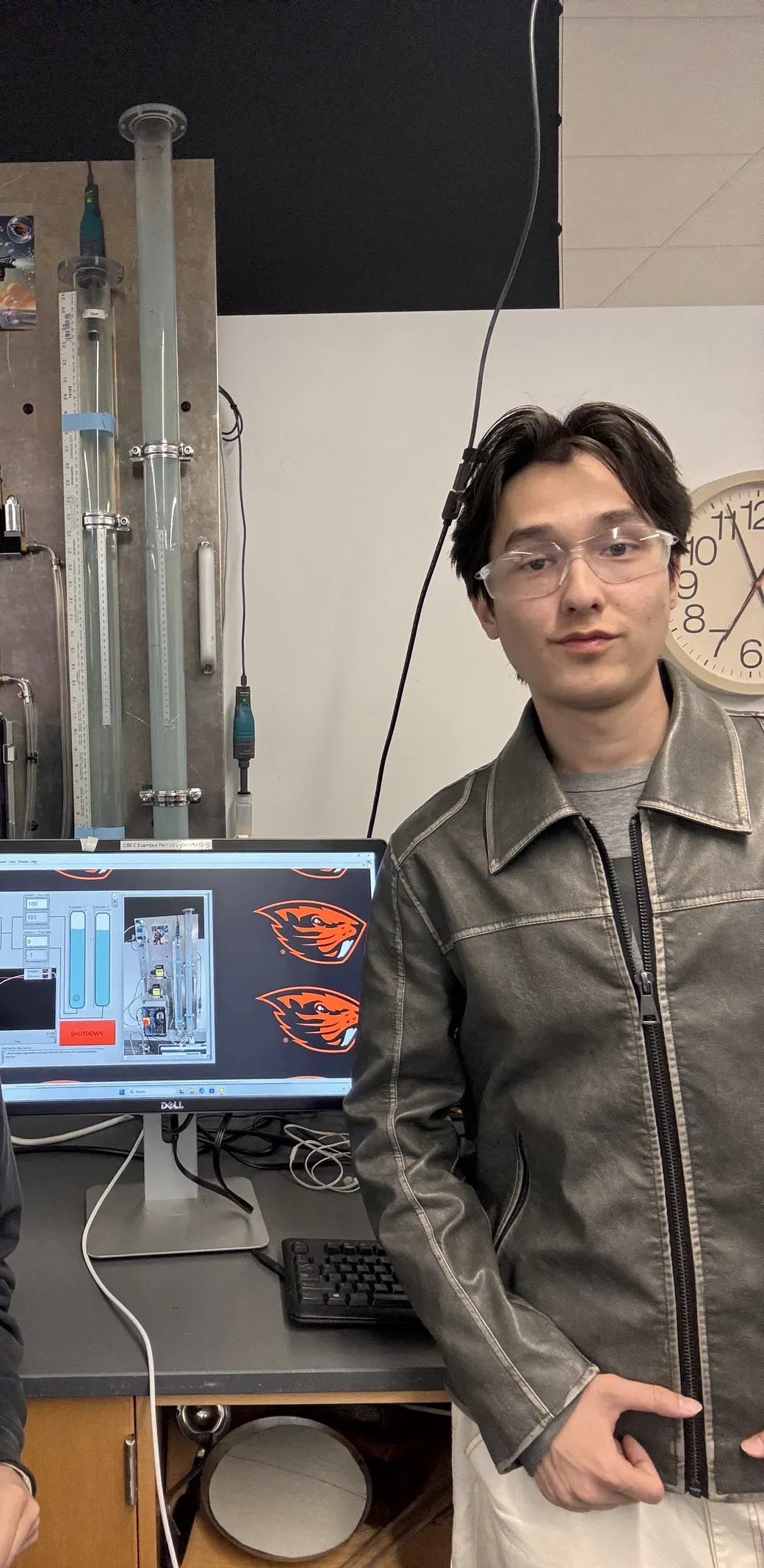 Jakhangir standing at the rig, the camera feed of the rig live in LabVIEW on the monitor beside him