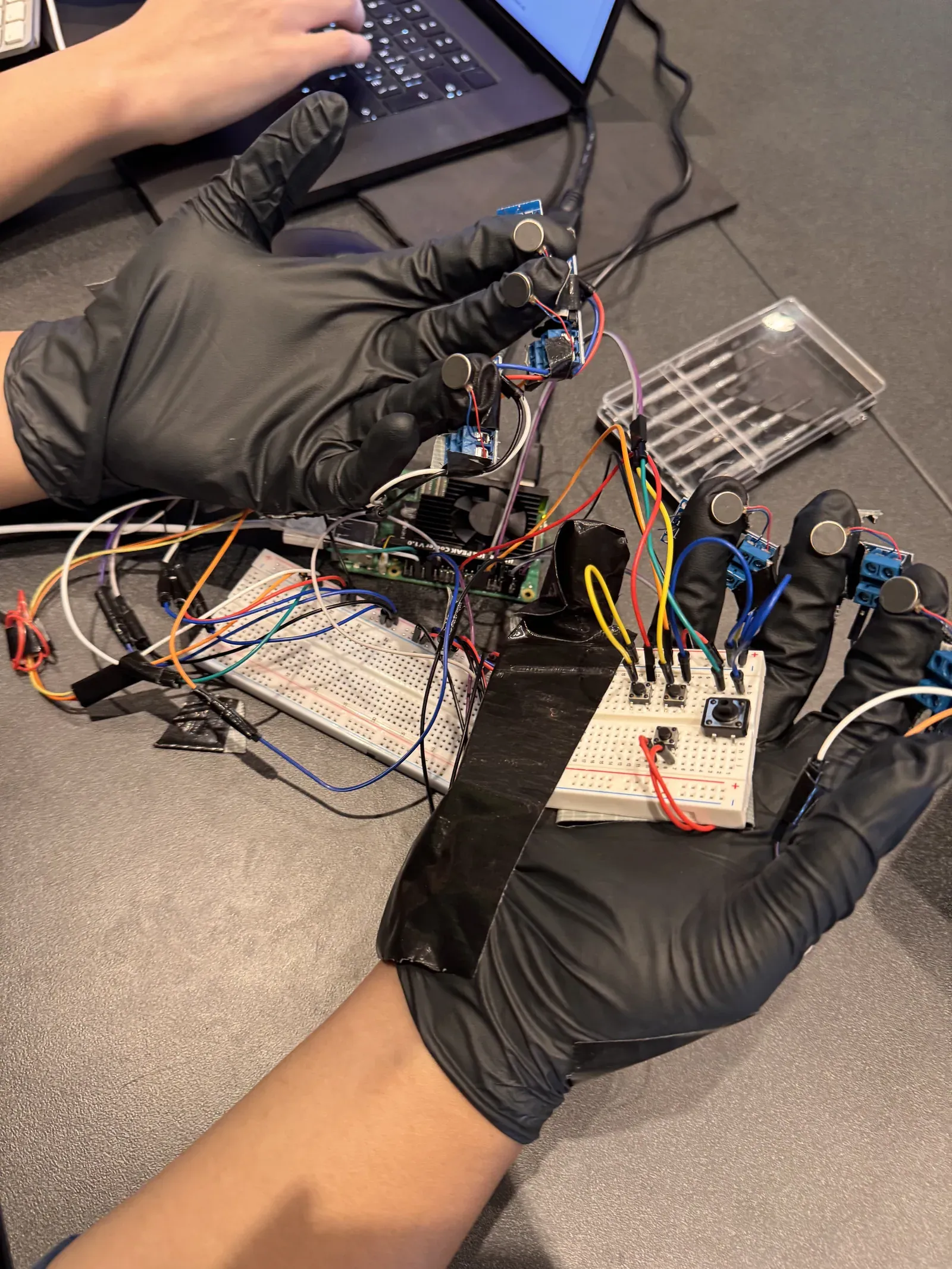 Both gloves worn, coin motors on three fingertips of each hand, the Raspberry Pi and the palm buttons