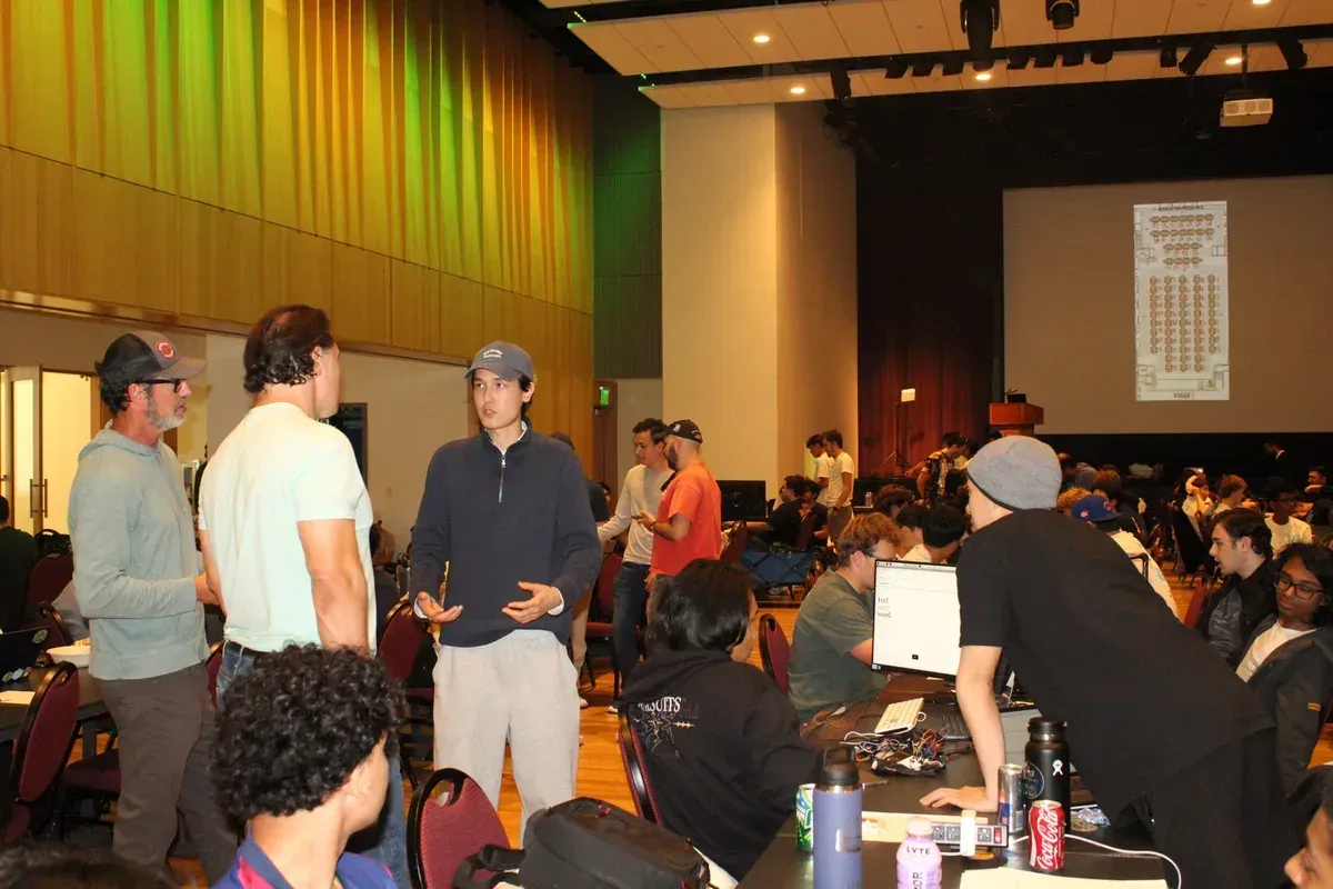 Jakhangir explaining the project to two visitors, the hardware on the table behind
