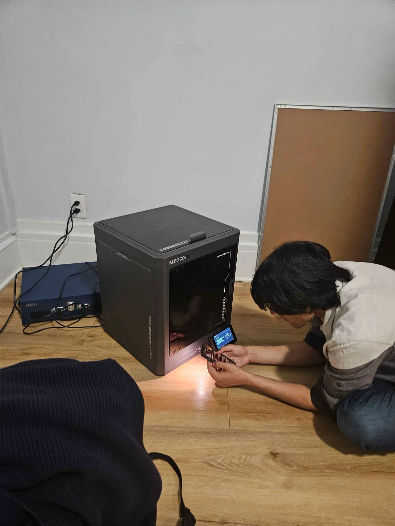 A teammate kneeling at an Elegoo 3D printer, printing the headband