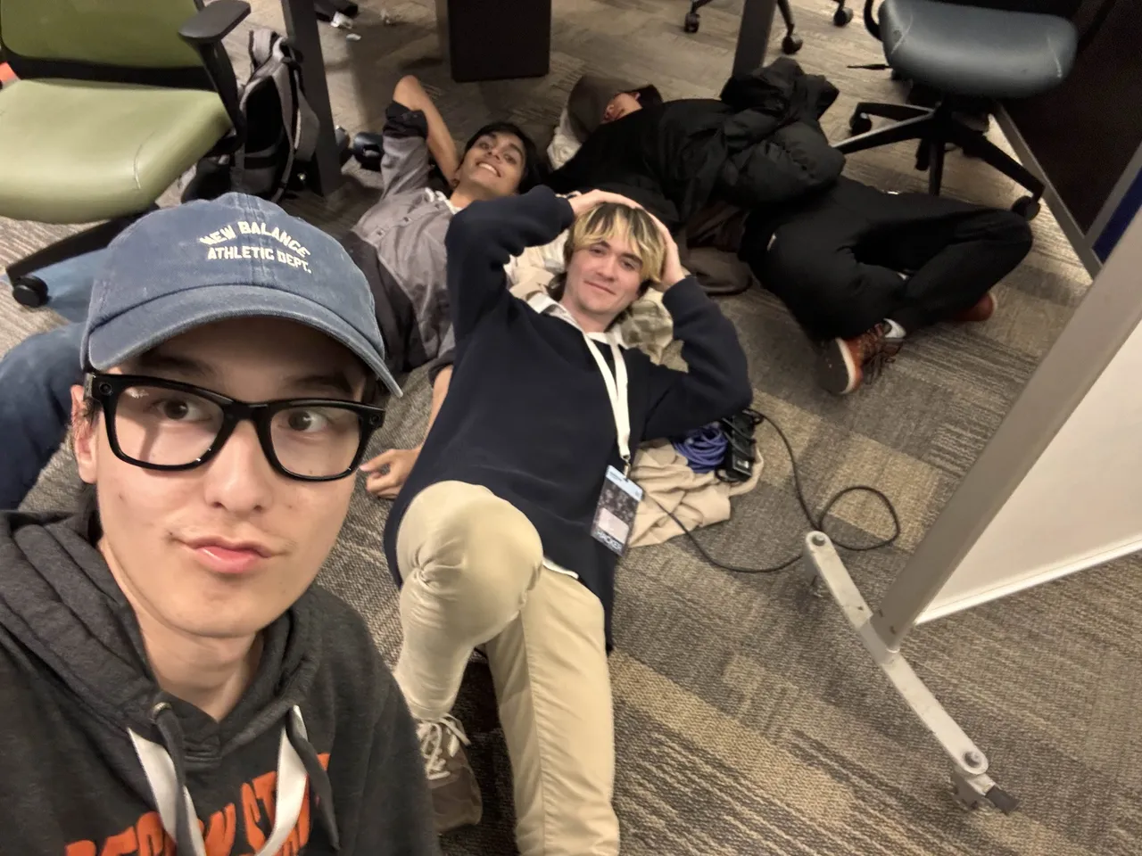 Jakhangir and two teammates lying on the floor between the chairs at night