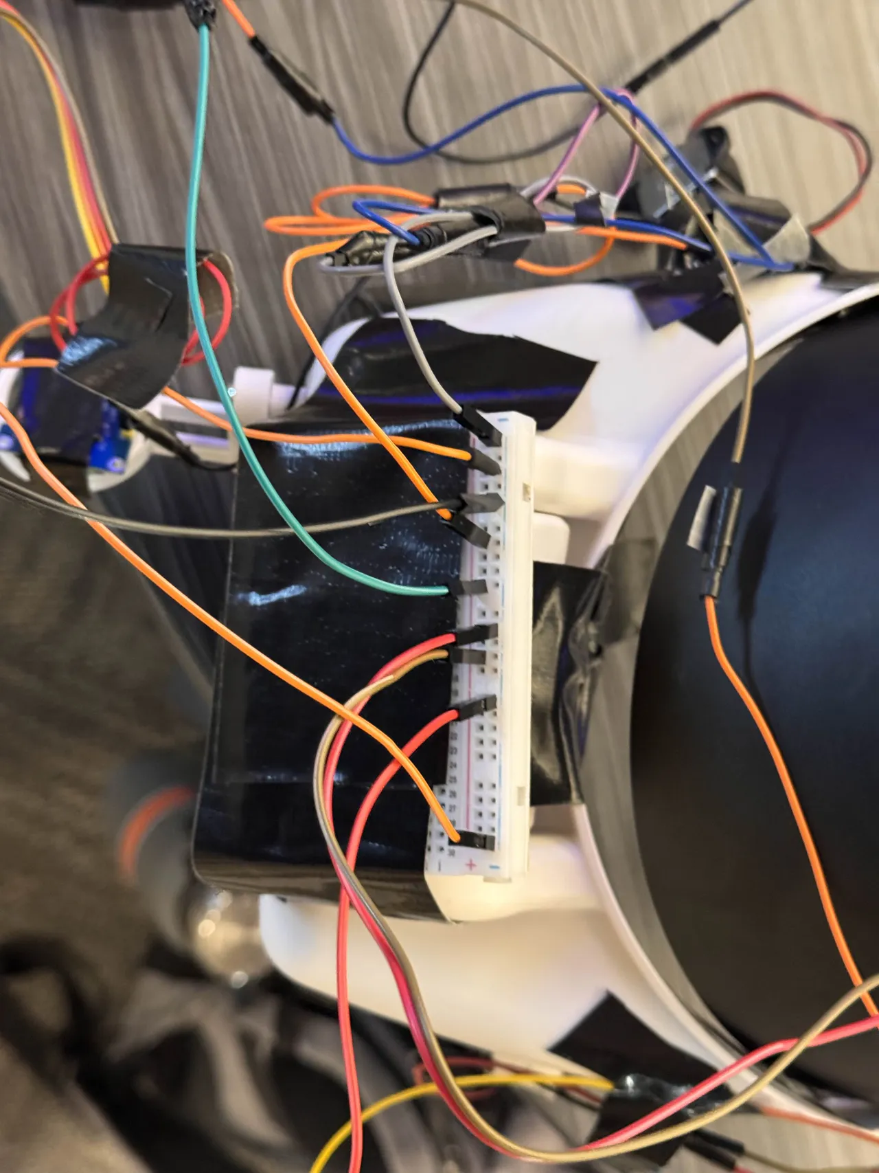 A breadboard taped to the printed headband, jumper wires fanning out of it